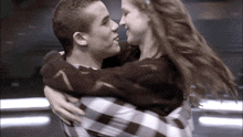 a man in a plaid shirt holds a girl in his arms