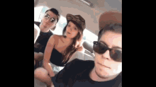 a group of people are sitting in the back seat of a car and one of them is wearing sunglasses