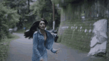 a woman in a blue jacket is running down a street .