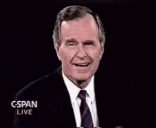 a man in a suit and tie is giving a speech in front of a black background that says cspan live