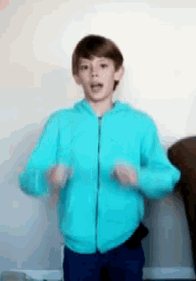 a young boy wearing a blue jacket is dancing in a living room .