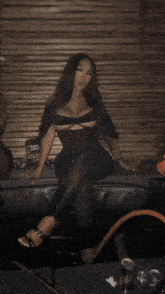 a woman in a black dress is sitting on a chair