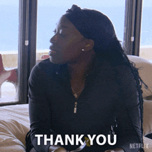 a woman is sitting on a bed with the words thank you written below her