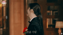 a woman in a tuxedo with a flower in her hair has korean writing on the bottom