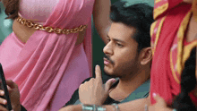 a man in a pink saree is pointing at a woman in a red saree