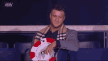 a man in a suit and scarf is holding a poker chip with the aew logo on it
