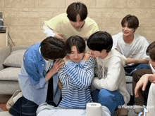 a group of young men are sitting on a couch with a roll of toilet paper in the foreground .
