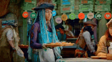 a woman in a pirate hat is holding a tray of cookies .
