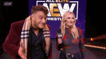 a man and a woman are standing in front of a sign that says all elite aew