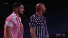 a wrestler is kneeling down in front of a aew wrestling dynamite sign