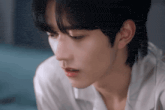a close up of a young man 's face with a white shirt on