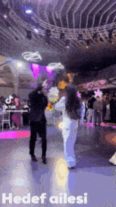 a man and a woman are dancing in a room with the words hedef ailesi on the bottom right
