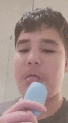 a young man is brushing his teeth with an electric toothbrush in a bathroom .