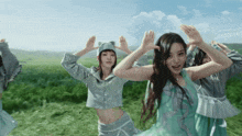 a group of women are dancing in a field with their arms in the air
