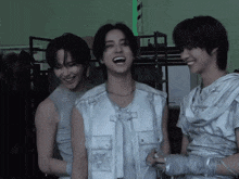 a man in a white vest is laughing while standing next to two other men