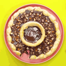 a pizza with chocolate sauce and nuts on it on a pink plate