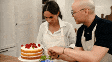 a man and a woman are looking at a cake