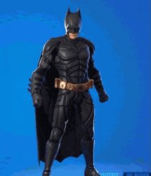 a man in a batman suit is standing in front of a blue background .