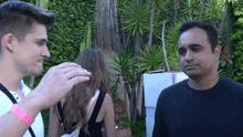 a man is touching another man 's hair while a woman looks on