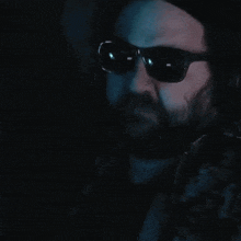 a man with a beard wearing sunglasses and smoking a cigarette