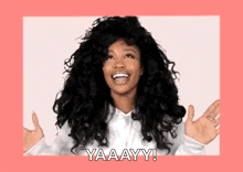 a woman with curly hair is smiling and making a funny face with her hands outstretched .