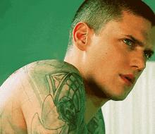 a man with a tattoo on his arm looks over his shoulder at the camera