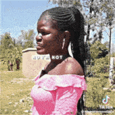 a woman wearing a pink off the shoulder top stands in front of a sign that says " no i 'm not "