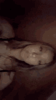 a woman is taking a selfie in a dark room while wearing a black bra and a necklace .