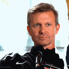 a man wearing a black nike jacket holds a microphone
