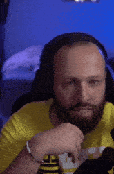a bald man with a beard wearing headphones and a yellow shirt that says ' lg ' on it