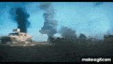 a military vehicle is driving down a road in front of a large explosion