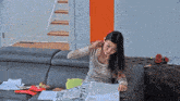 a woman sits on a couch looking at a newspaper that says ' a ' on it