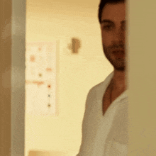 a man in a white shirt is standing in a doorway looking at the camera .