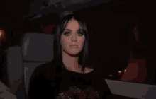 a woman with long black hair is sitting in a car looking at the camera .