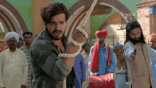 a man is tied up with a rope and another man is pointing a gun at him .