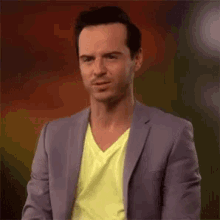 a man wearing a purple jacket and a yellow shirt is making a funny face .