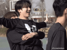 a man in a black shirt with the letter m on it holds another man in his arms