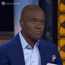 a man in a blue suit and white shirt is sitting in front of a cbs dragonsden sign
