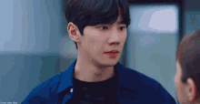 a man in a blue shirt and black shirt is looking at another man .