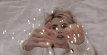 a woman is laying on a bed holding a string of lights .