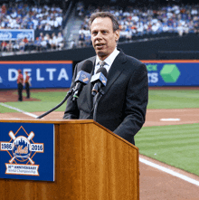 a man stands at a podium with a sign that says mets