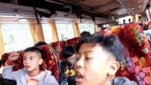 a group of young boys are sitting on a bus and one of them is wearing sunglasses
