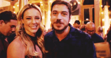 a man and a woman are standing next to each other and smiling for the camera .