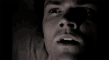a close up of a man 's face with his mouth open in the dark