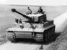 a black and white photo of a military tank on a dirt road