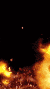 a close up of a fire with sparks flying in the air
