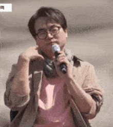 a man wearing glasses is holding a microphone