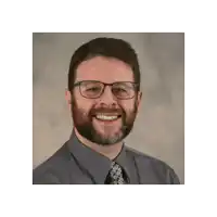 a man with glasses and a beard smiles for a photo