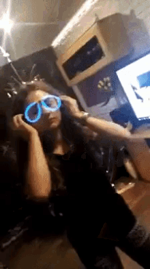 a woman wearing glow in the dark glasses looks at herself in a mirror