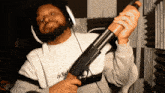 a man wearing headphones is holding a shotgun with the word adio on his sweatshirt